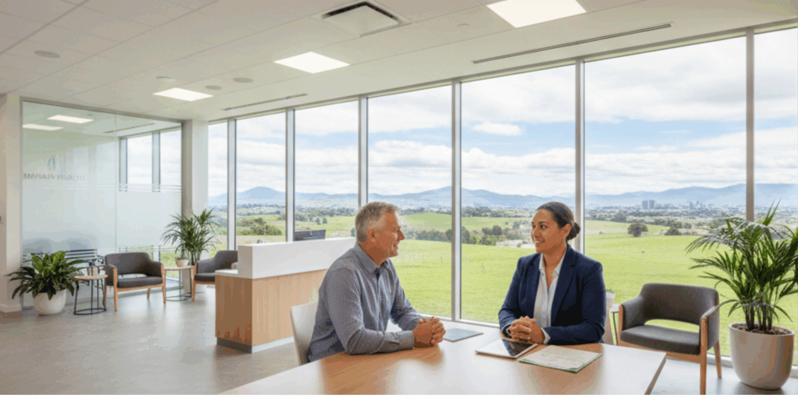 Professional GP consulting with patient in modern New Zealand clinic with natural landscape visible through windows